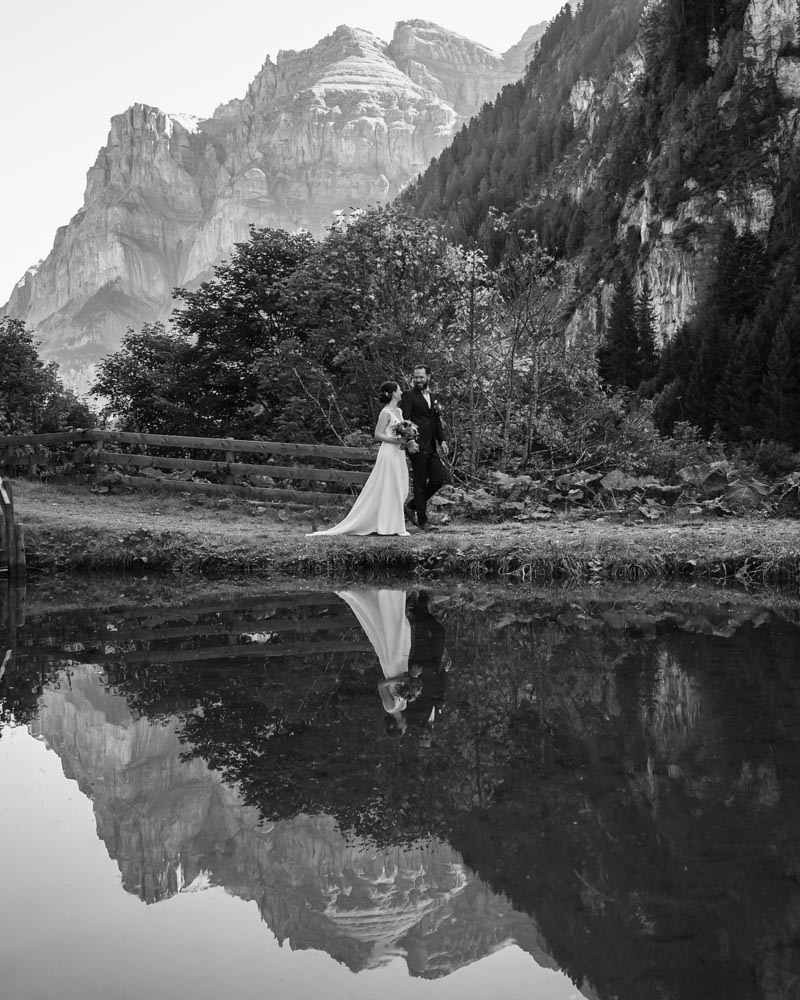 Berghochzeit in Graubünden – Schwarzweiss Hochzeitsfotografie Brautpaar bei einer Berghochzeit in Graubünden vor alpiner Bergkulisse mit Spiegelung im See – fotografiert von Hochzeitsfotograf Christian Meixner aus Zürich.