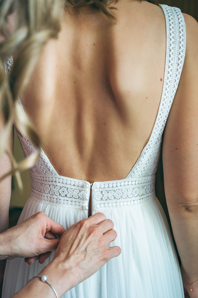 Getting Ready der Braut im Hotel Sorell Zürichberg Detailaufnahme der Braut beim Getting Ready im Hotel Sorell Zürichberg in Zürich – das Brautkleid wird geschlossen, fotografiert von Hochzeitsfotograf Christian Meixner.